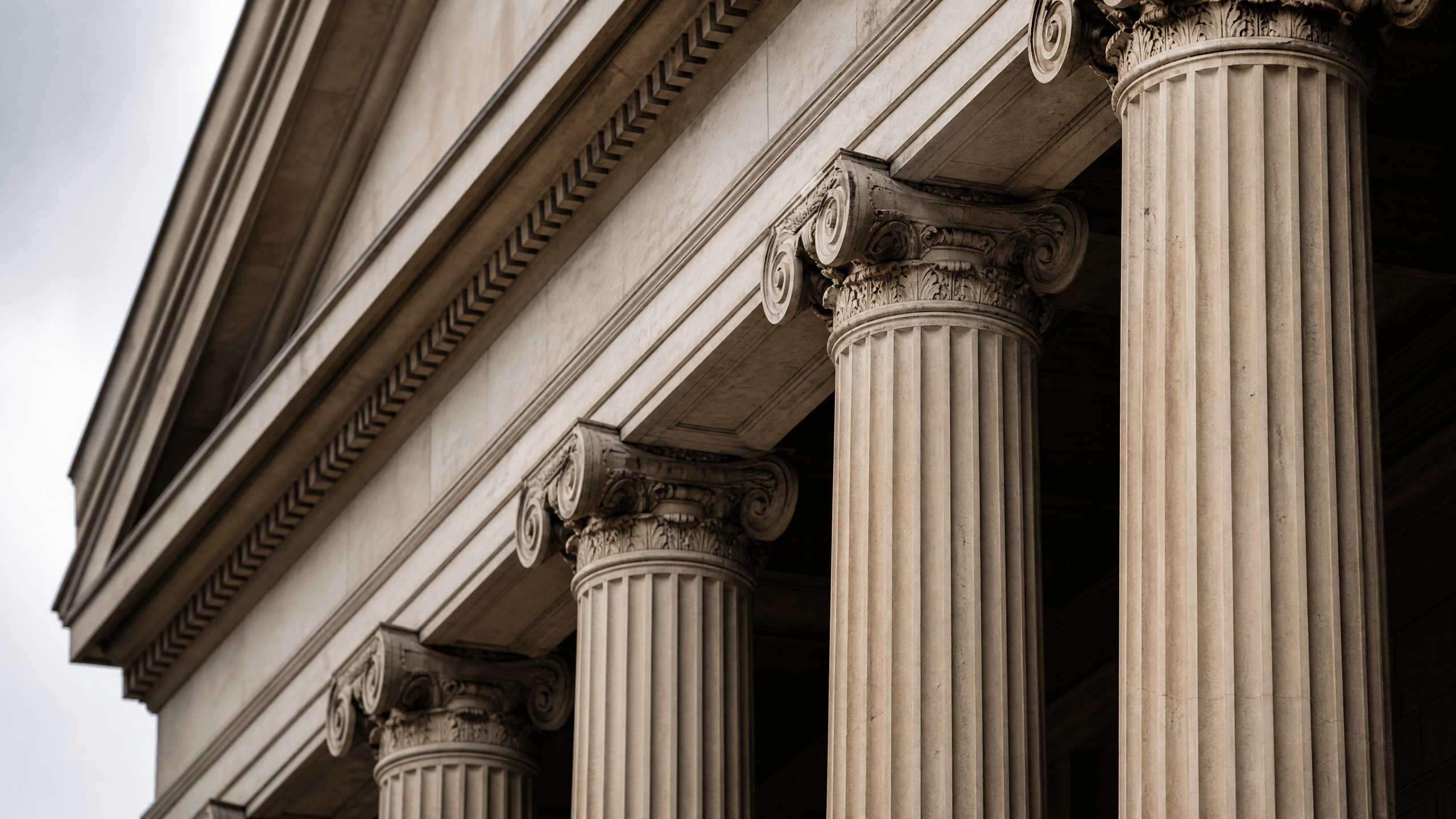 Tight crop of stone courthouse columns and steps, with no signage or seals visible, suggesting a neutral judicial setting.
